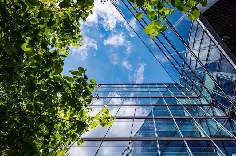 View into the blue sky with office building facades and trees