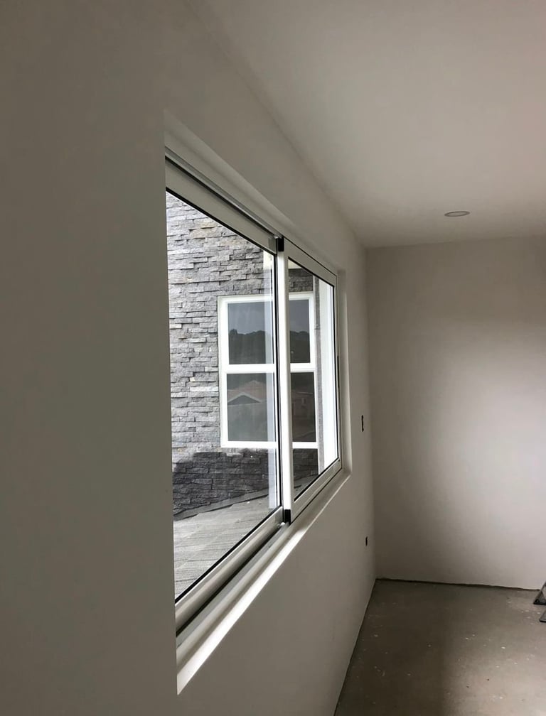 Puerta corrediza de vidrio con marco blanco hacia pared de ladrillo