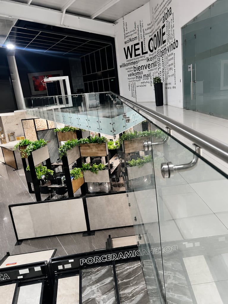 Modern stairwell with a welcome sign on the wall, glass railing, and potted plants on a tiered display below