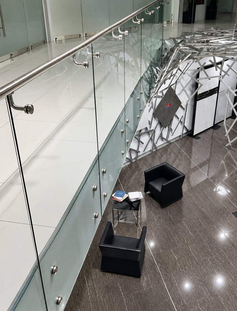 Modern stairwell with glass railing and hangers holding white towels or linens above black storage bins on grey floor