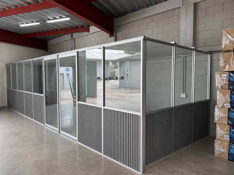Metal and glass industrial enclosure or kennel structure in a warehouse with corrugated metal roof
